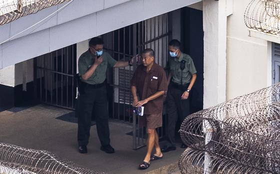 Former Hong Kong media tycoon Jimmy Lai is seen from above walking in prison clothes next to two prison guards, July 28, 2023.