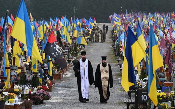 Priest visit the Lychakiv cemetery on the Day of the Armed Forces of Ukraine, in Lviv on Dec. 6, 2024, amid the Russian invasion of Ukraine. (Yuriy Dyachyshyn/AFP/Getty Images/TNS)