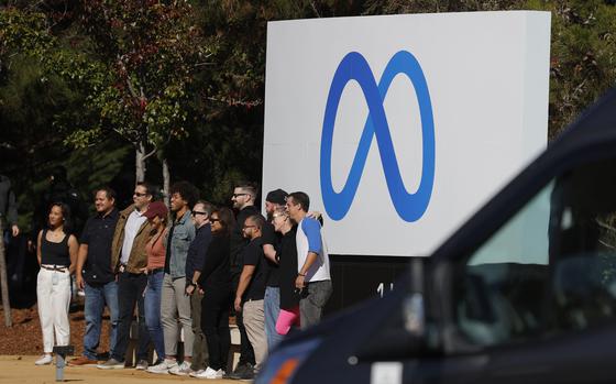 Facebook employees gather in front of a sign displaying a new logo and the name 'Meta' in front of Facebook headquarters on October 28, 2021 in Menlo Park, Calif. (Justin Sullivan/Getty Images/TNS)