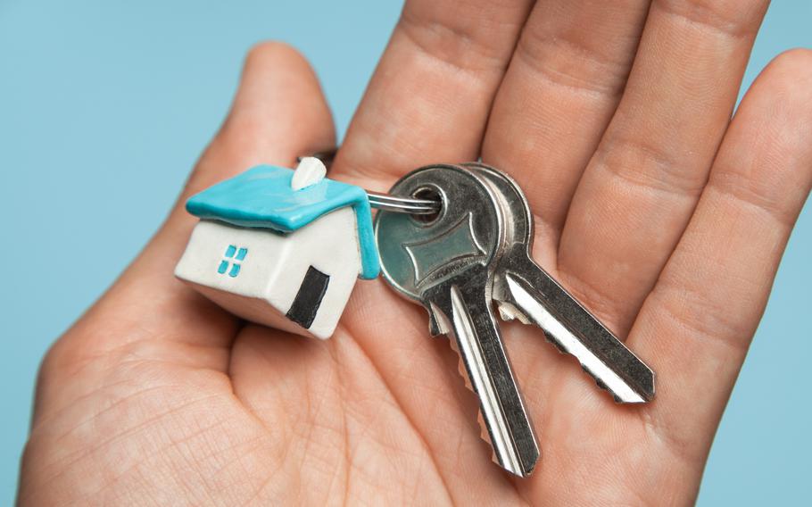 Keys and key ring with a house charm on a hand. 