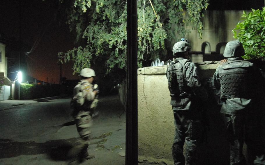 An American soldier and his interpreter peek over a wall 