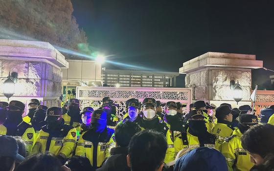 A line of police face demonstrators outside the gates of the National Assembly.