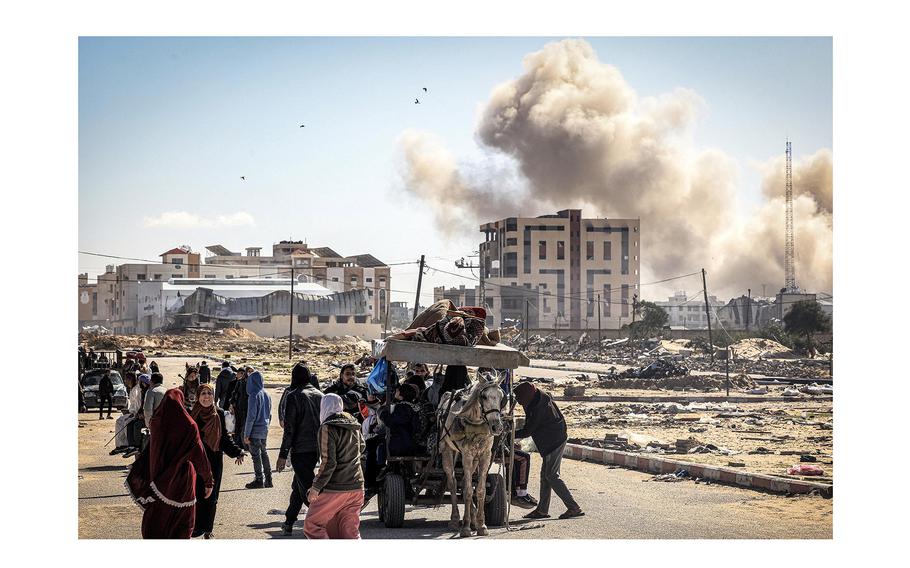 Smoke from bombardment billows in the background as displaced Palestinians flee from Khan Yunis in the southern Gaza Strip on Jan. 30, 2024, amid the ongoing conflict between Israel and the Palestinian militant group Hamas. 