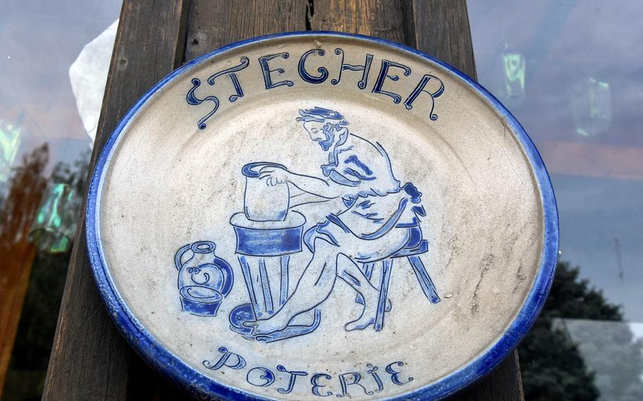 A ceramic plate hangs on a wooden post outside Pascal Stecher’s pottery studio on a quiet street in Betschdorf, France. The village is famous for its Alsatian potters, who for generations have created gray stoneware with cobalt blue patterns.