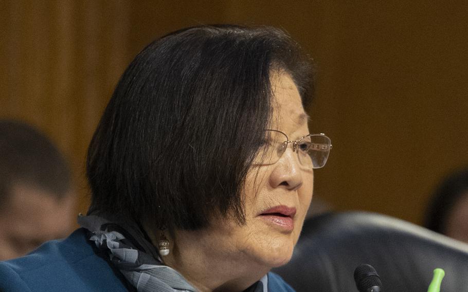 Hirono is wearing blue, seated and speaking.