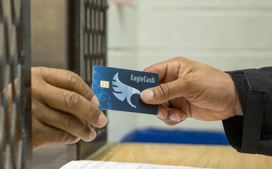 A Fort Jackson Army Military Pay Office military pay technician hands a new EagleCash card to an Army Basic Combat Training trainee at Fort Jackson, South Carolina, April 20, 2022. EagleCash is a stored value card that serves as a cash management tool where funds are loaded to a card and linked to the cardholder's personal account at a financial institution, using a self-service kiosk. (U.S. Army photo by Mark R. W. Orders-Woempner)