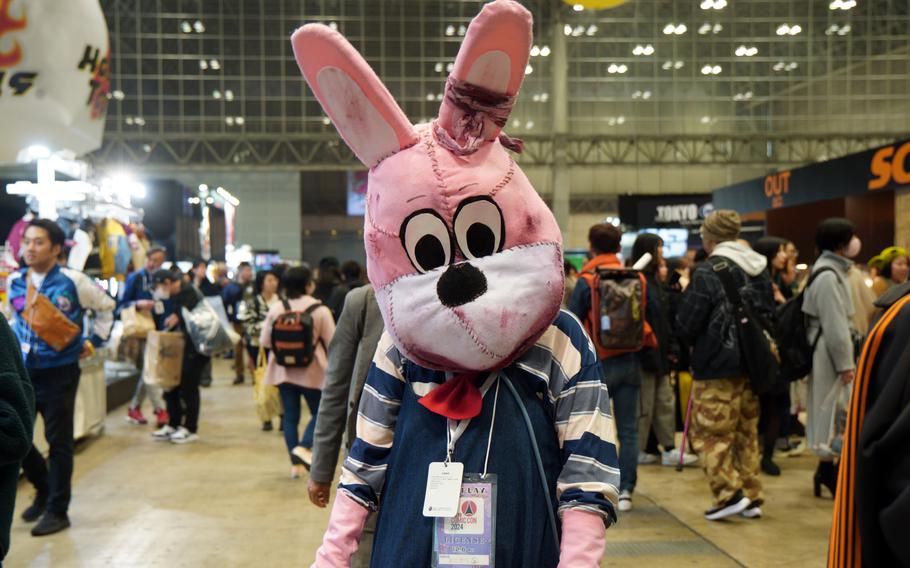 A person is dressed in a bloody pink bunny suit and wearing a striped navy shirt.