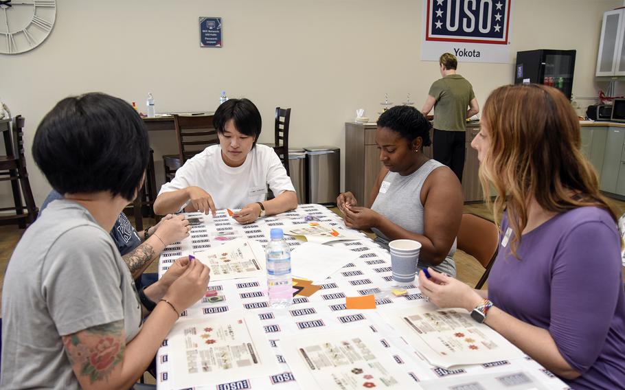 Sgt. Ayami Konishi, of the Japan Ground Self-Defense Force, helps U.S. service members construct paper ornaments called tsumami during a cultural exchange at the USO on Yokota Air Base, Japan, July 22, 2023. 