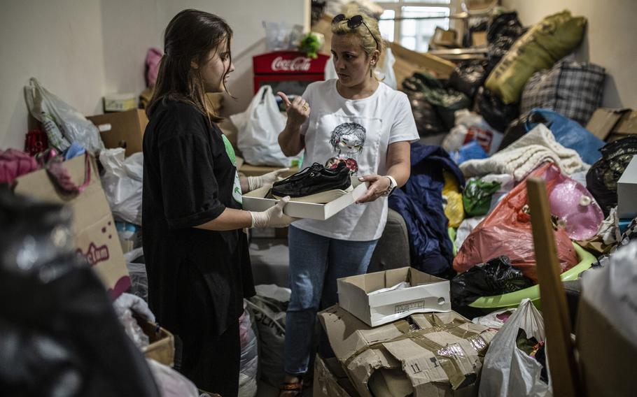 Iryna Arziaieva, 42, and her daughter Mariia,13, sorting donated clothing and shoes at the community center where they volunteer distributing clothing to those in need in Vyshneve, a Kyiv suburb on July 26, 2022.