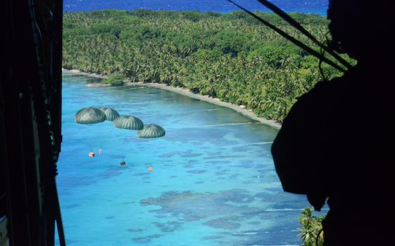 Senior Airman Juan Lucero, a loadmaster with the 36th Airlift Squadron at Yokota Air Base, Japan, watches Operation Christmas Drop bundles drift to islanders on Ifalik, part of the Federated States of Micronesia, Dec. 11, 2024.