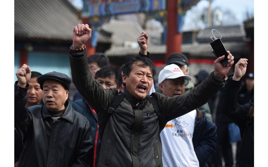 Relatives of passengers missing on Malaysia Airlines flight MH370 shout slogans outside the Lama Temple in Beijing on March 8, 2016.