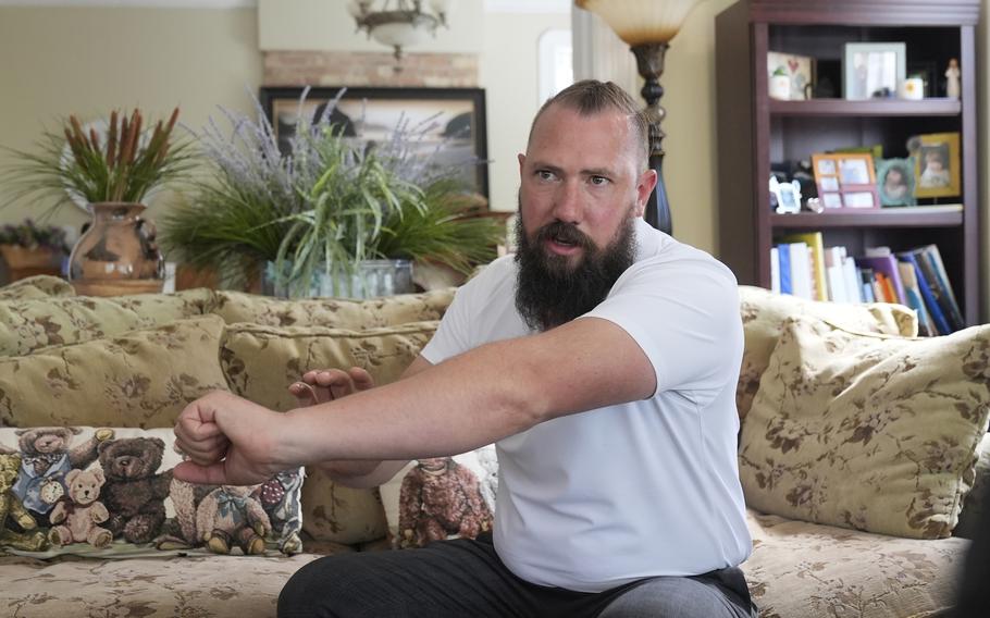 Ben Powell, who has a beard and is wearing a white shirt, speaks to a reporter.