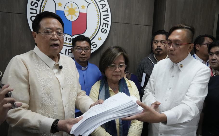 A woman stands between two men who are holding a thick stack of printed papers.