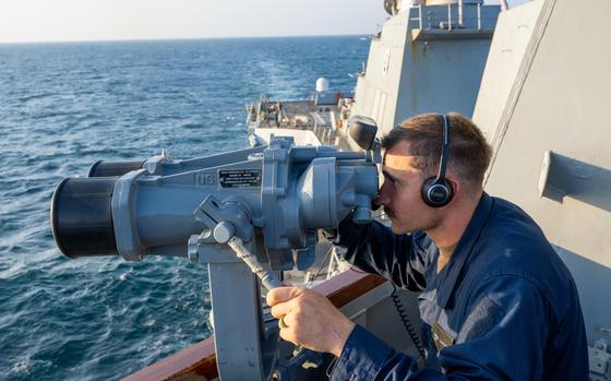 a-sailor-looks-through-binoculars-on-the-bridge-wing-aboard-the-arleigh