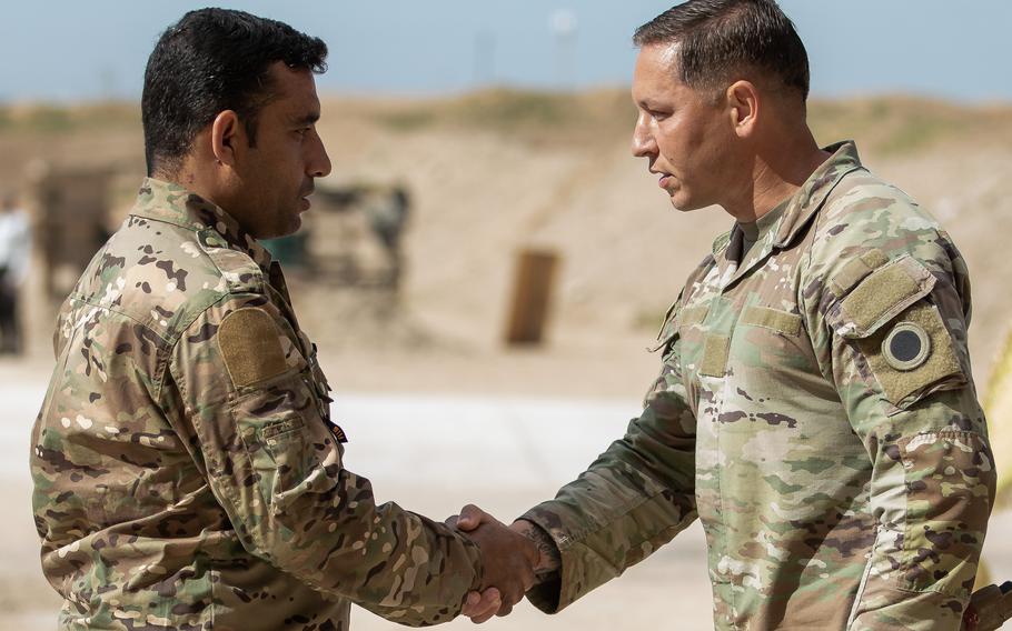 A Syrian detention facility guard trainer shakes hands with a coalition service member. 