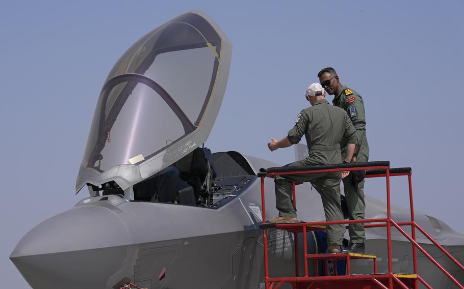 A U.S. airman shows an Indian naval officer the F-35 fighter jet during a static display.