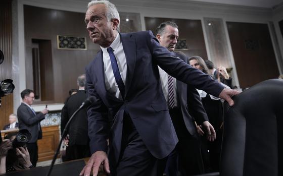 Robert F. Kennedy Jr. pulls a chair out at a table.