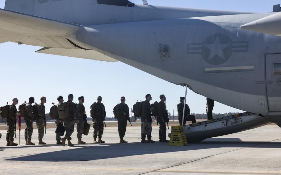 Marines in a line begin boarding the plane.