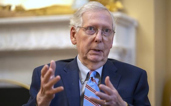 Mitch McConnell, wearing a dark suit, gestures with his hands as he sits for an interview.