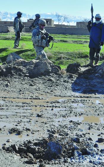 U.S. soldiers with the 4th Squadron, 73rd Cavalry Regiment and an Afghan National Police officer armed with a rocket-propelled grenade stand along a road opposite where a small bomb was triggered just after their convoy passed on Feb. 9, 2010