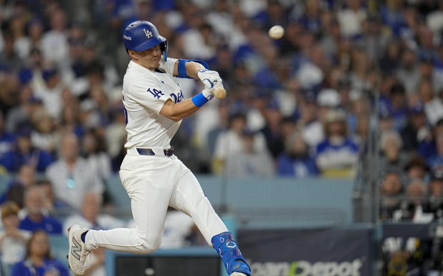 A man swings a bat at a baseball.