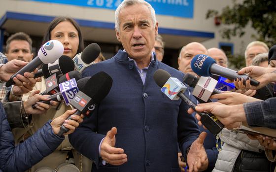 The far-right populist candidate Calin Georgescu speaks while surrounded by reporters and microphones in Bucharest, Romania, Oct. 1, 2024. 