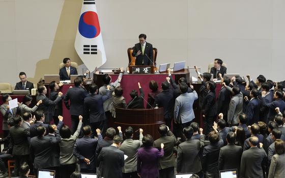 Lawmakers in suits raise their right fists as they surround South Korea’s National Assembly Speaker Woo Won Shik.