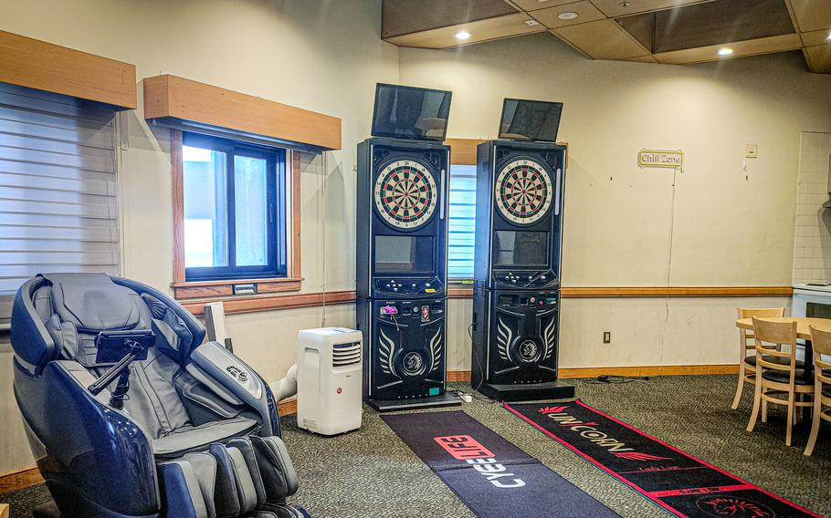 The inside of dormitory dayrooms at Kunsan Air Base showing a massage chair and dart boards.