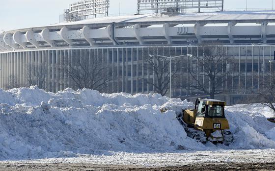 FILE - A vehicle pushes up pikes of snow after trucks dump their loads of snow in the parking lots of RFK Stadium in Washington, Monday, Jan. 25, 2016. (AP Photo/Susan Walsh, File)