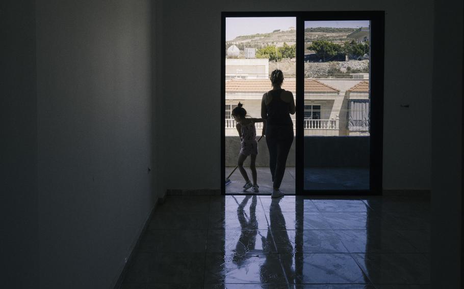 A woman and her young daughter clean an apartment where she is resettling with her family. Her previous apartment, in the same building, was burned down after an Israeli airstrike hit Wadi Jilo in early June. 