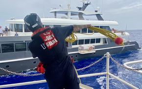 A crewman aboard the U.S. Coast Guard cutter Oliver Henry tosses a heaving line to set up a tow to the crew of the luxury yacht Black Pearl 1 after responding to a distress call on July 21, 2024. 