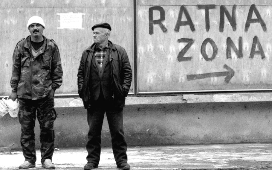 Two men standing in front of graffiti