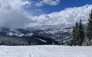 A view of the Vail slopes and mountains. There is a sign indicating which direction to go to find the Game Creek Bowl, among other places. 