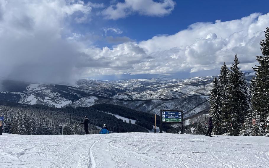 A view of the Vail slopes and mountains. There is a sign indicating which direction to go to find the Game Creek Bowl, among other places. 