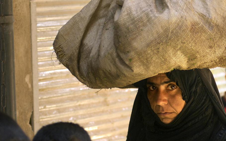 An Iraqi woman snakes through the heart of Oubaidy’s market with a large load in this eastern Baghdad town.  