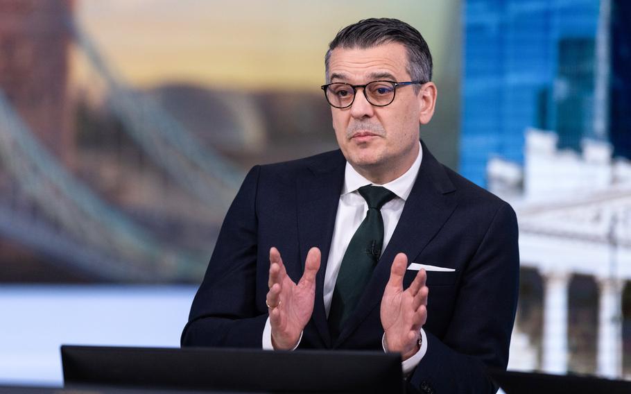 The CEO of a German radar manufacturer wearing a suit and holding both hands out to gesture as he talks.