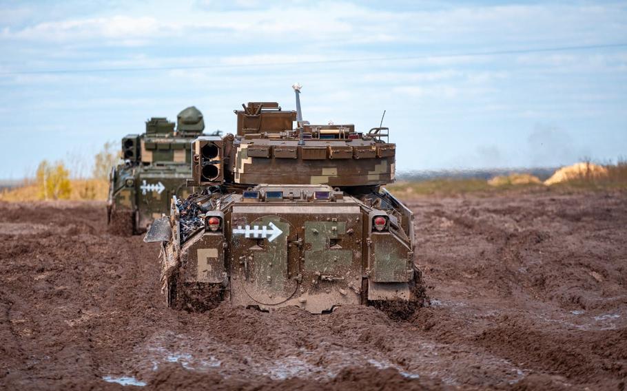 Bradley Fighting Vehicles maneuver through muddy terrain in Ukraine.