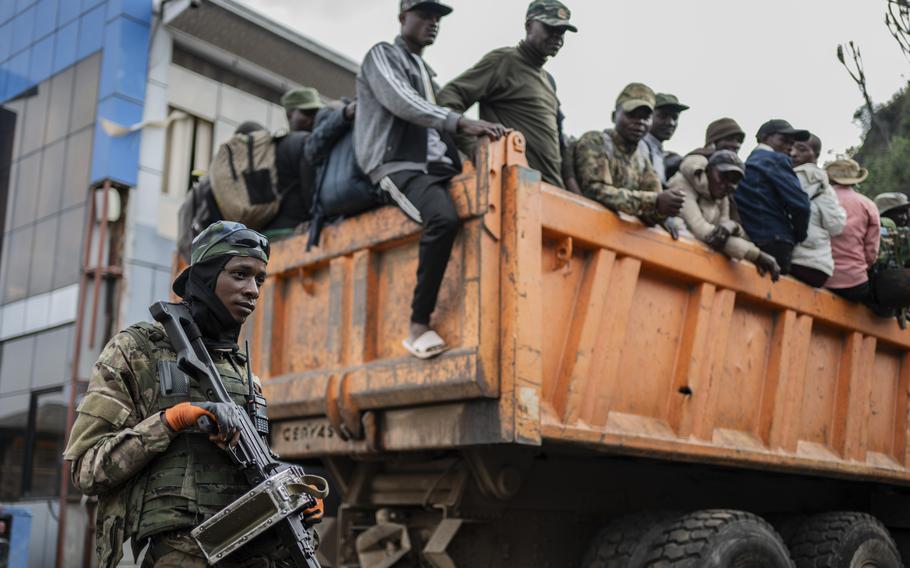 Soldiers in the back of an orange truck holding guns.