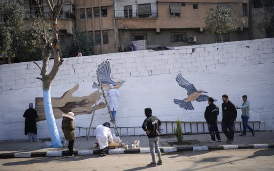 A group of young volunteers paints a mural symbolizing peace on a wall on the outskirts of Damascus, Syria, Sunday, Jan. 12, 2025. (AP Photo/Mosa'ab Elshamy)