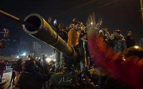 Men stand on top of a tank and cheer.