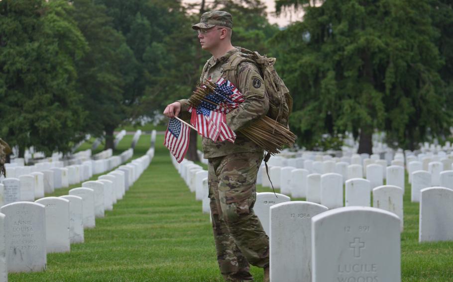 Sgt. Steven Khaytsis places flags in section 12 of Arlington National Cemetery on Thursday, May 23, 2024, for the annual “Flags In” event to honor fallen service members for Memorial Day.  