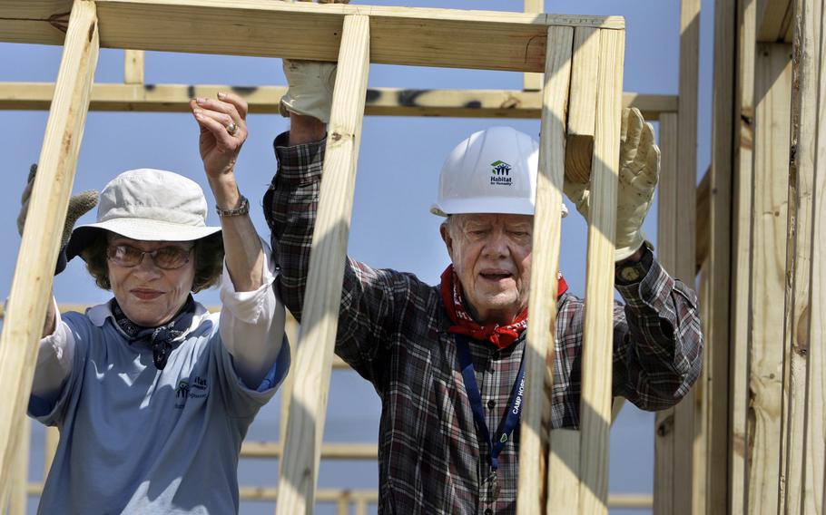 Rosalynn and Jimmy lift a wood frame into place.