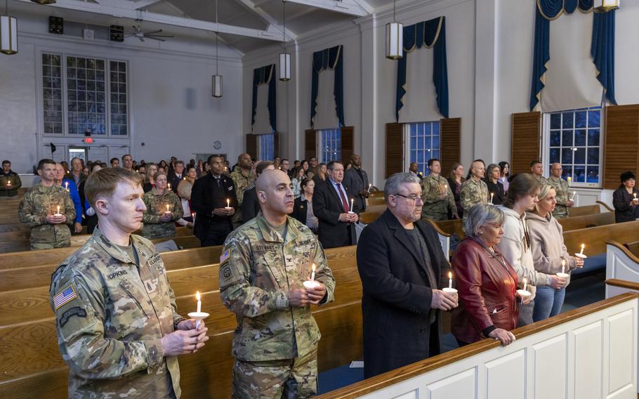 Mourners in a chapel holding candles.