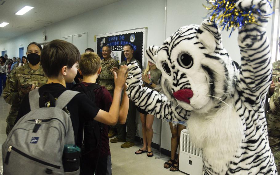 Yokota Middle School's mascot, White Tiger, high-fives students on their first day of classes at Yokota Air Base, Japan,  Monday, Aug. 19, 2024. 