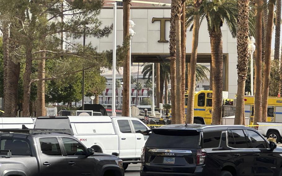 The entrance to a hotel is seen through palm trees from across the street.