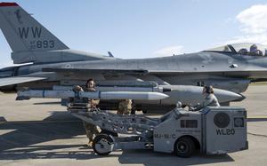 Airmen loading missiles onto a jet.