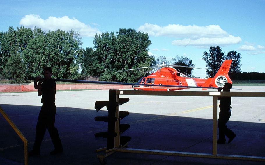 Two helicopter mechanics carry a rotor blade to mount on an HH-65 “Dolphin” helicopter at Coast Guard Air Station Detroit, Michigan.