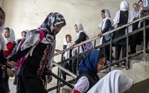 Girls in headscarves walk down a flight of stairs.