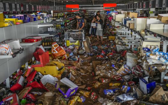 People pick up goods in a supermarket affected by the floods in Valencia, Spain, Thursday, Oct. 31, 2024. (AP Photo/Manu Fernandez)