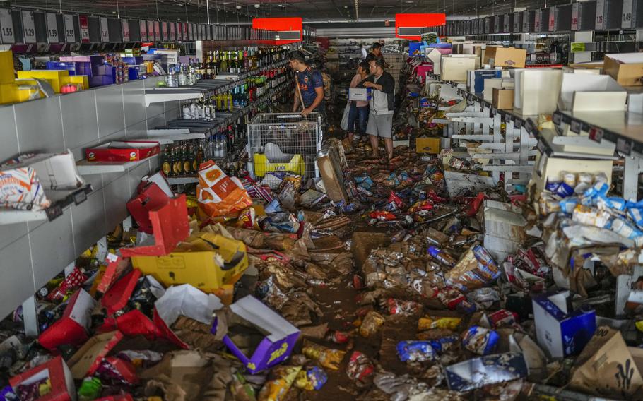 People clean a supermarket destroyed by floods. in Valencia.